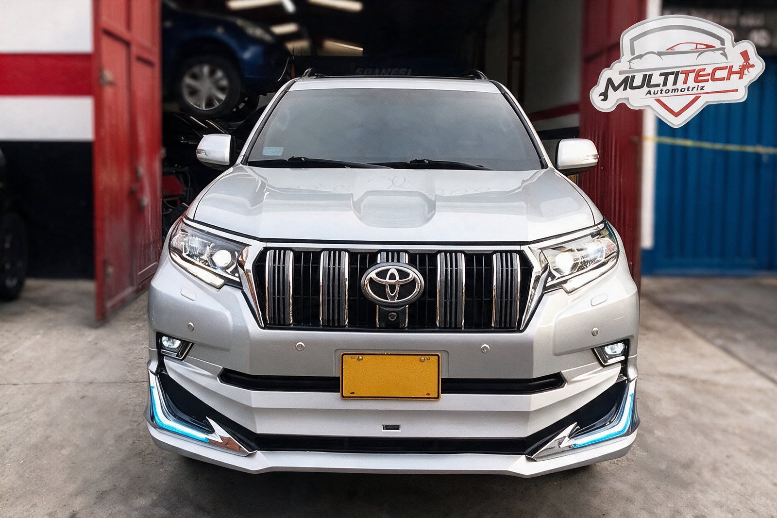 Toyota Prado blanca en la entrada del taller junto al banco de enderezado Spanesi